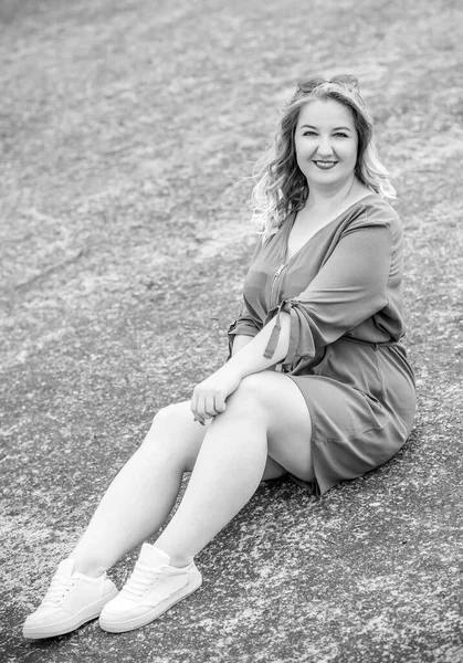 Happy woman of plus size, walks in the city enjoying life. Young lady with excess weight, stylishly dressed at the city park .Natural beauty