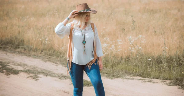 Woman Plus size in American country style black boho jacket, with a fringe, shirt and cowboy hat at nature