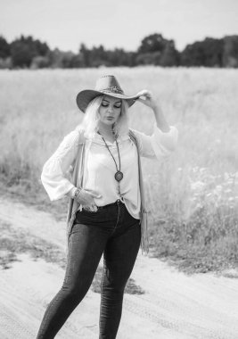 Woman Plus size in American country style black boho jacket, with a fringe, shirt and cowboy hat at nature
