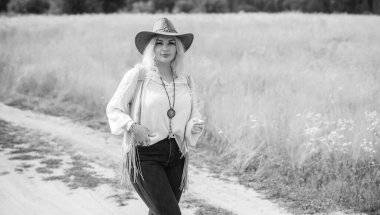 Woman Plus size in American country style black boho jacket, with a fringe, shirt and cowboy hat at nature