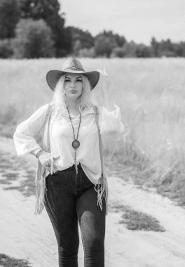 Woman Plus size in American country style black boho jacket, with a fringe, shirt and cowboy hat at nature