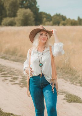 Woman Plus size in American country style black boho jacket, with a fringe, shirt and cowboy hat at nature