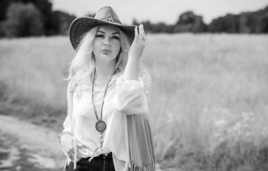 Woman Plus size in American country style black boho jacket, with a fringe, shirt and cowboy hat at nature