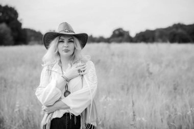 Woman Plus size in American country style black boho jacket, with a fringe, shirt and cowboy hat at nature
