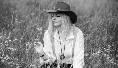 Woman Plus size in American country style black boho jacket, with a fringe, shirt and cowboy hat at nature