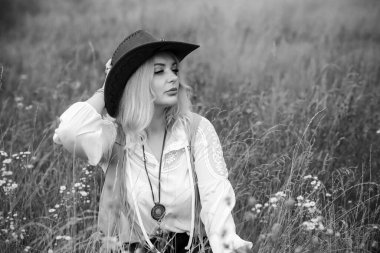 Woman Plus size in American country style black boho jacket, with a fringe, shirt and cowboy hat at nature