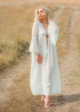 Ethnic hippie woman posing in boho long white lace dress at nature. Concept of ethnos style