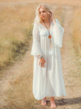 Ethnic hippie woman posing in boho long white lace dress at nature. Concept of ethnos style