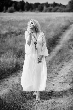 Ethnic hippie woman posing in boho long white lace dress at nature. Concept of ethnos style