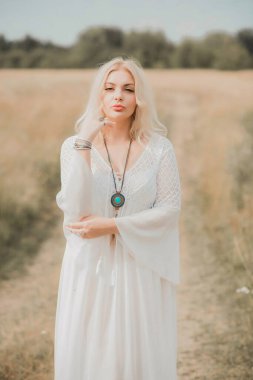 Ethnic hippie woman posing in boho long white lace dress at nature. Concept of ethnos style