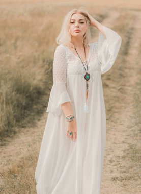 Ethnic hippie woman posing in boho long white lace dress at nature. Concept of ethnos style