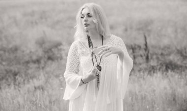 Ethnic hippie woman posing in boho long white lace dress at nature. Concept of ethnos style