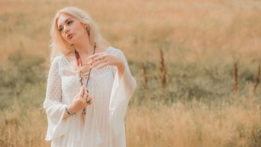 Ethnic hippie woman posing in boho long white lace dress at nature. Concept of ethnos style