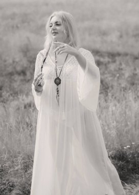 Ethnic hippie woman posing in boho long white lace dress at nature. Concept of ethnos style