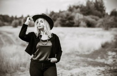 Woman in American country style,  suede leather boho jacket and cowboy hat at nature