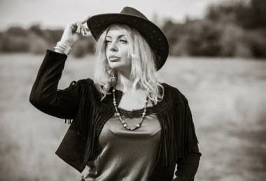 Woman in American country style,  suede leather boho jacket and cowboy hat at nature