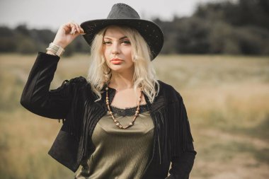 Woman in American country style,  suede leather boho jacket and cowboy hat at nature