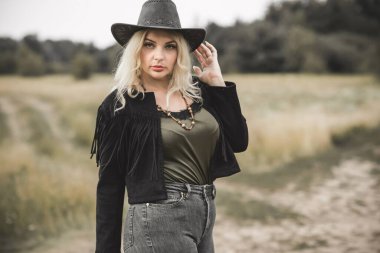 Woman in American country style,  suede leather boho jacket and cowboy hat at nature