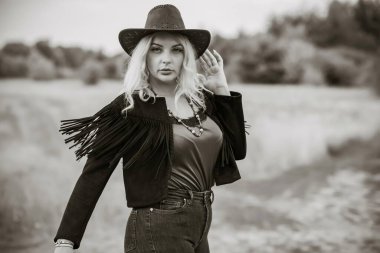 Woman in American country style,  suede leather boho jacket and cowboy hat at nature