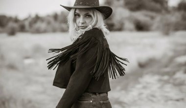 Woman in American country style,  suede leather boho jacket and cowboy hat at nature