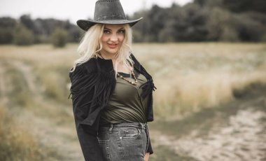 Woman in American country style,  suede leather boho jacket and cowboy hat at nature