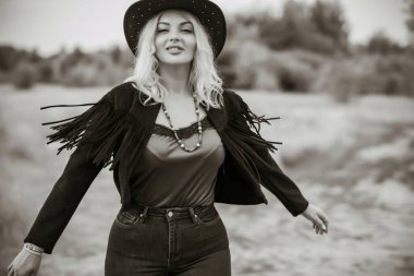 Woman in American country style,  suede leather boho jacket and cowboy hat at nature