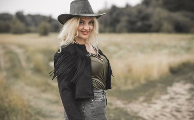 Woman in American country style,  suede leather boho jacket and cowboy hat at nature