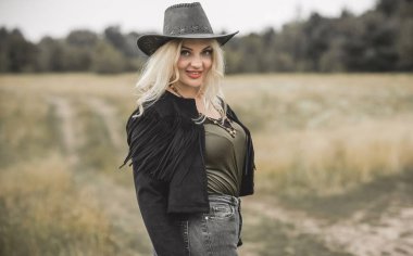 Woman in American country style,  suede leather boho jacket and cowboy hat at nature