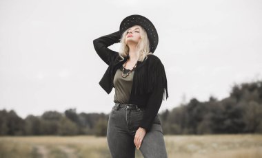 Woman in American country style,  suede leather boho jacket and cowboy hat at nature