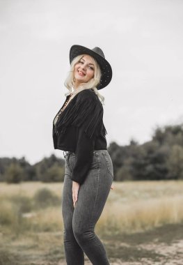 Woman in American country style,  suede leather boho jacket and cowboy hat at nature