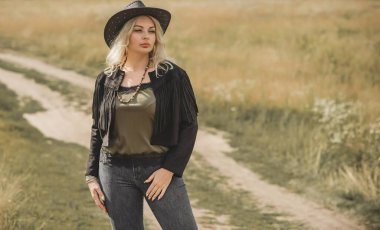 Woman in American country style,  suede leather boho jacket and cowboy hat at nature