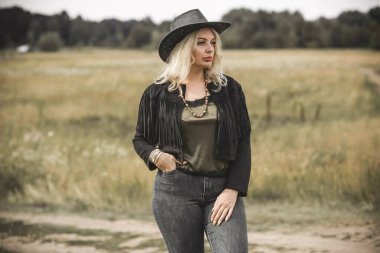 Woman in American country style,  suede leather boho jacket and cowboy hat at nature