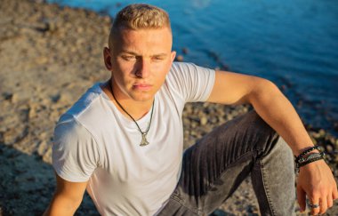 Young guy at beach in tranquility mood, rest in vacation. Summer portrait of handsome men at beach, concept of vacation, rest time 
