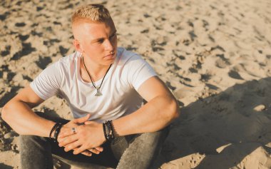 Young guy at beach in tranquility mood, rest in vacation. Summer portrait of handsome men at beach, concept of vacation, rest time 
