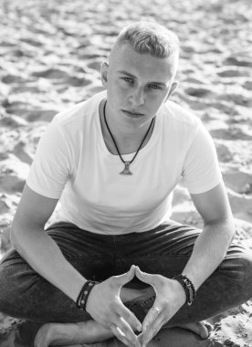 Young guy at beach in tranquility mood, rest in vacation. Summer portrait of handsome men at beach, concept of vacation, rest time 