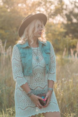 Vintage Boho style, blonde tan plus size woman in dress, wool hat and boots at sunset, fashionable clothes and details.  