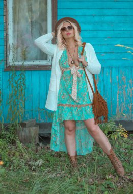 Vintage Boho style, blonde tan plus size woman in dress, wool hat and boots at sunset, fashionable clothes and details.  