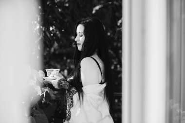 Balkonda bir fincan çay, şefkat ve kadınların duygusallığı ile kadınsı seksi bir kadın.