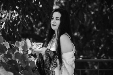 Balkonda bir fincan çay, şefkat ve kadınların duygusallığı ile kadınsı seksi bir kadın.