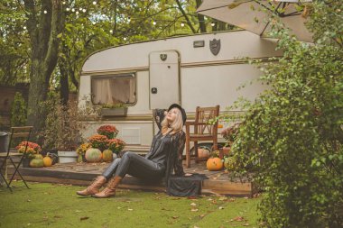 Sonbahar bahçesinde Boho tarzı giyinmiş, felsefi bir havası olan zarif sarışın bir kadın. Güzel aksesuarlı ve doğal bir tarzı olan bir bayan.