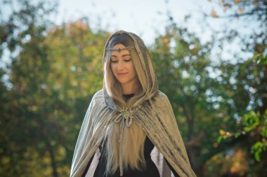 İskandinav konsepti, eski dünya büyüsü, İskandinav konsepti, İskandinav tarzı uzun sarı saçlı, elf, gri mantolu fantezi kadın. Cadılar Bayramı kostümü