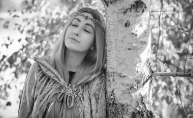 İskandinav konsepti, eski dünya büyüsü, İskandinav konsepti, İskandinav tarzı uzun sarı saçlı, elf, gri mantolu fantezi kadın. Cadılar Bayramı kostümü