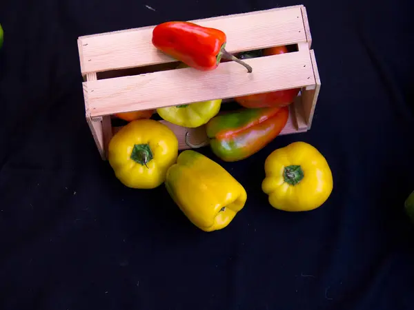 Sağlıklı beslenme kavramı. Hasat festivali, taze yemek. Kilo vermek için diyet. Biberler ahşap kutunun üstünde. Yiyecek kaynağı. Eko ürünlerin tepside teslimatı. Siyah arkaplan