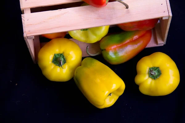Sağlıklı beslenme kavramı. Hasat festivali, taze yemek. Kilo vermek için diyet. Biberler ahşap kutunun üstünde. Yiyecek kaynağı. Eko ürünlerin tepside teslimatı. Siyah arkaplan