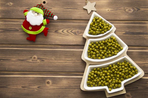 Happy New Year 2022. New Year\'s green peas in saucers in the form of a Christmas tree. Christmas wooden background with white numbers 2022