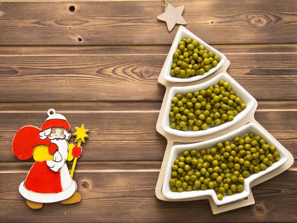 Mutlu yıllar 2022. Yeni yılın yeşil bezelyeleri bir noel ağacı şeklinde çay tabağı şeklinde. Beyaz numaraları 2022 olan Noel ağacı arka planı.