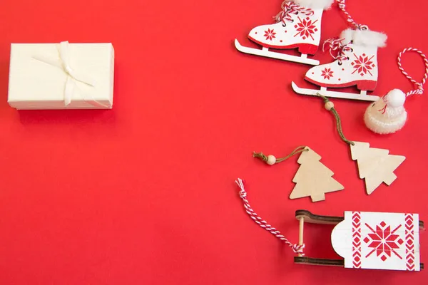 Kırmızı arka planda yeni yıl planı, eldivenler, kızak, ahşap yeni yıl treni, ahşap Noel ağaçları. 2022