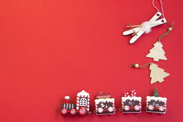 Kırmızı arka planda yeni yıl planı, eldivenler, kızak, ahşap yeni yıl treni, ahşap Noel ağaçları. 2022