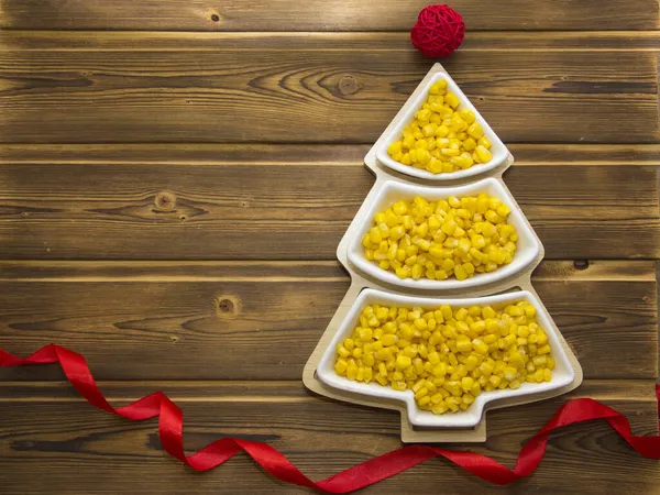 Mutlu yıllar 2022. Yeni yıl sarı mısırı bir noel ağacı şeklinde çay tabağı şeklinde. Beyaz numaraları 2022 olan Noel ağacı arka planı.