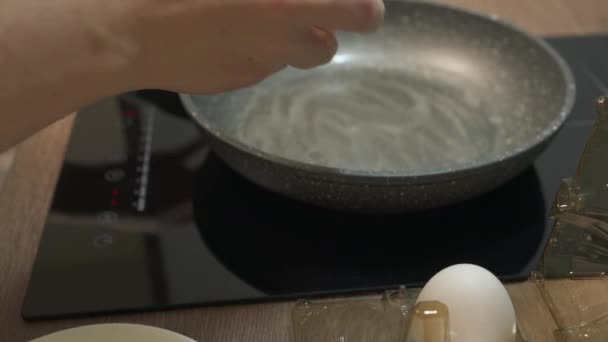 Verse eieren breken in hete koekenpan op fornuis. Gebakken eieren in een niet-kleverige pan. — Stockvideo